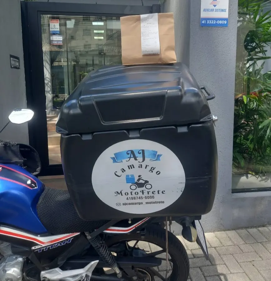 Baú de entrega identificado da AJ Camargo com uma encomenda